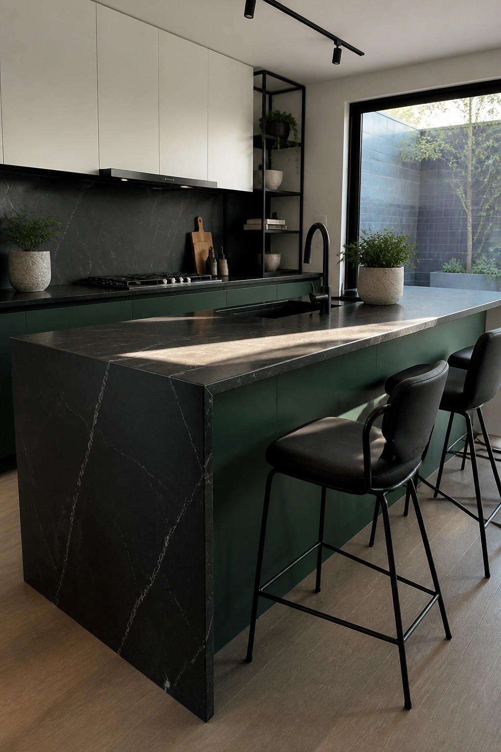A modern kitchen with deep green lower cabinets and island paired with black marble counters.