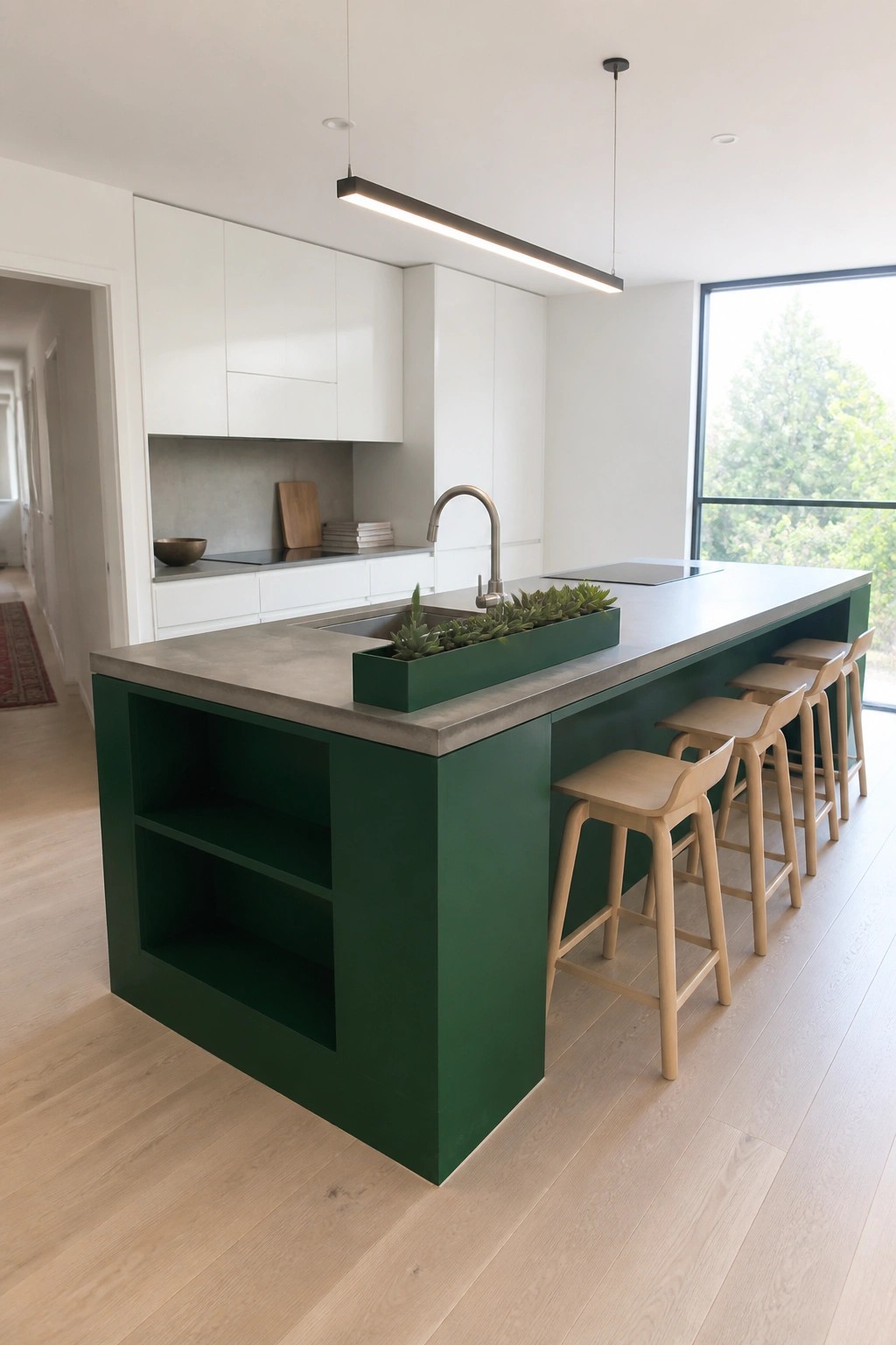 A modern kitchen featuring a deep green island with open shelving and a concrete countertop.