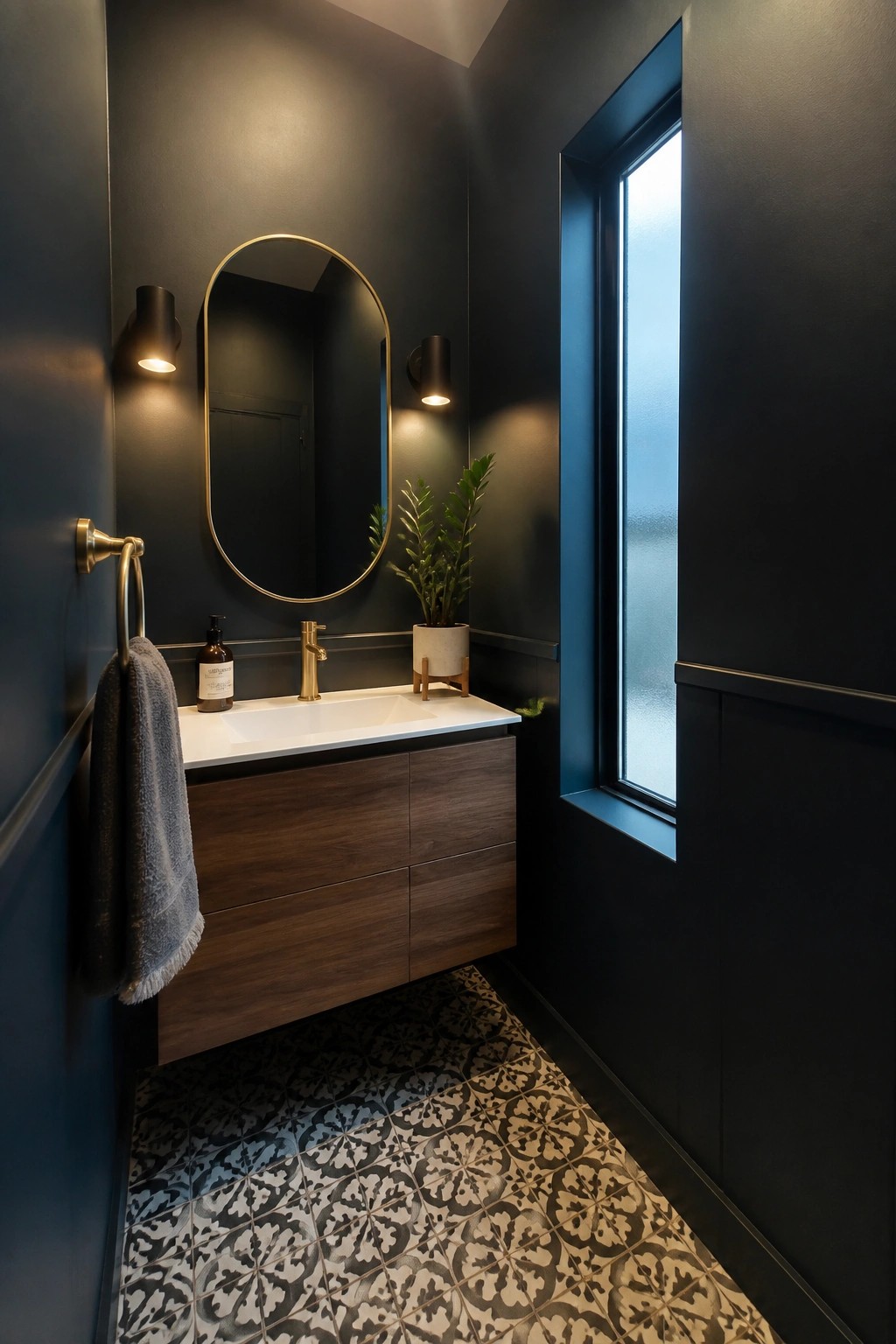 Modern bathroom with dark walls, wooden vanity, oval gold mirror, and patterned tiles.