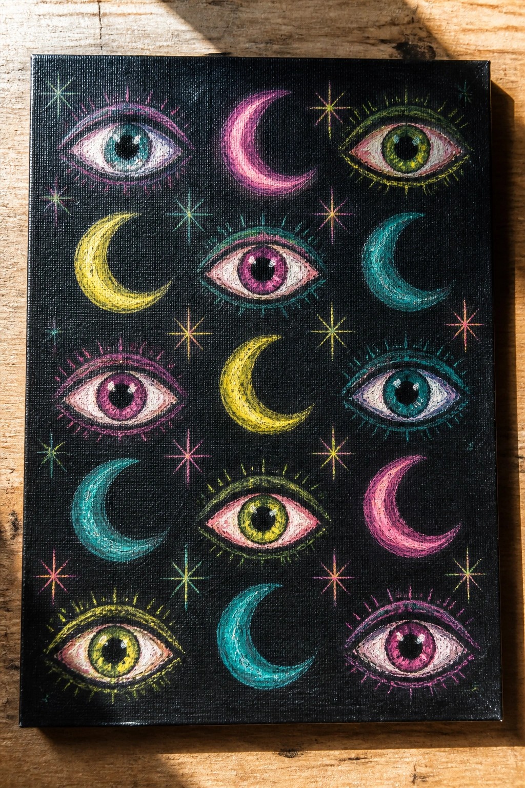 Colorful eyes, crescent moons, and stars painted on a black canvas