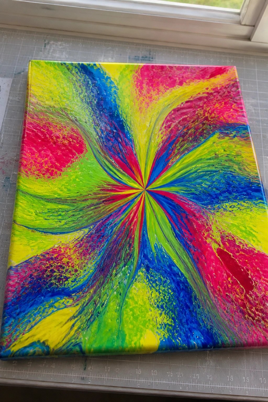 Vivid abstract fluid art canvas with colorful radial swirls in pink blue yellow green.