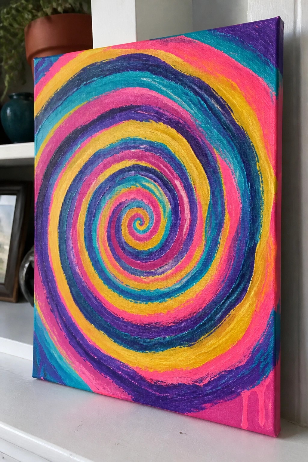 Vibrant multicolored spiral painting on canvas with dripping pink paint at bottom