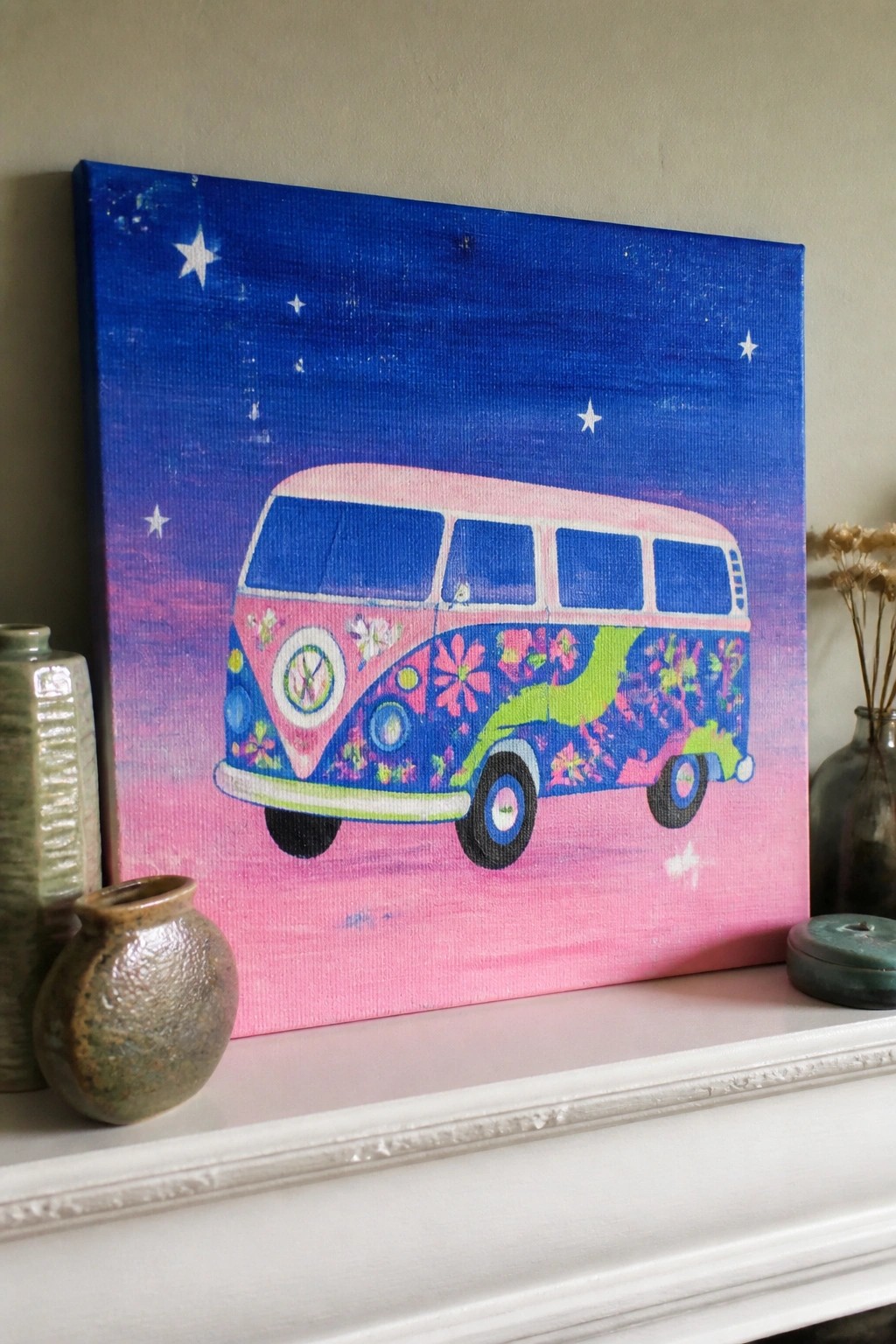 Colorful flower-decorated VW van painting on canvas beside ceramic vases on mantel