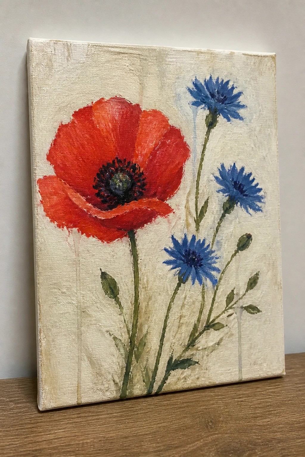 Large red poppy with blue cornflowers and green stems on canvas painting.