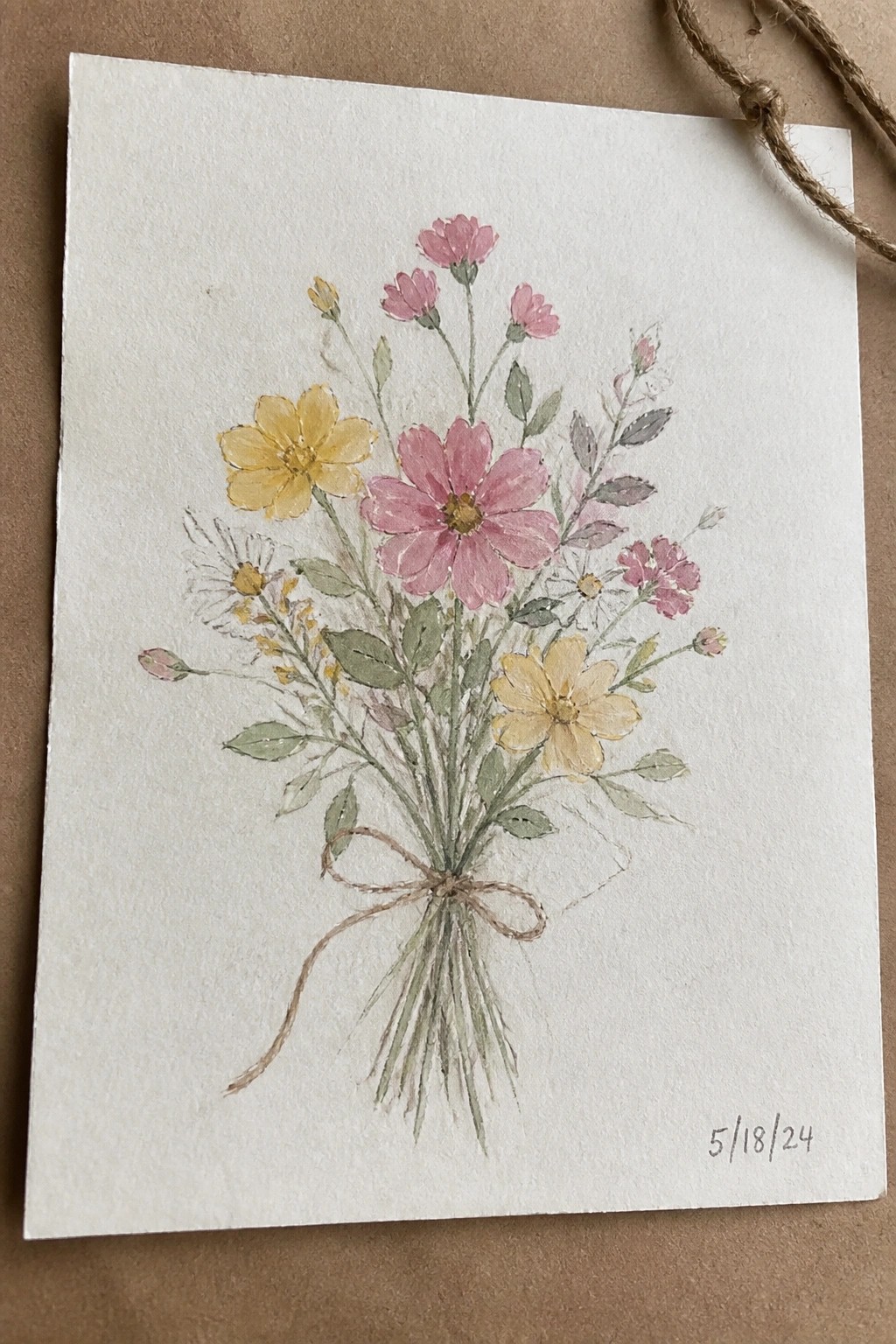 Watercolor bouquet of pink and yellow wildflowers tied with twine bow on white paper.