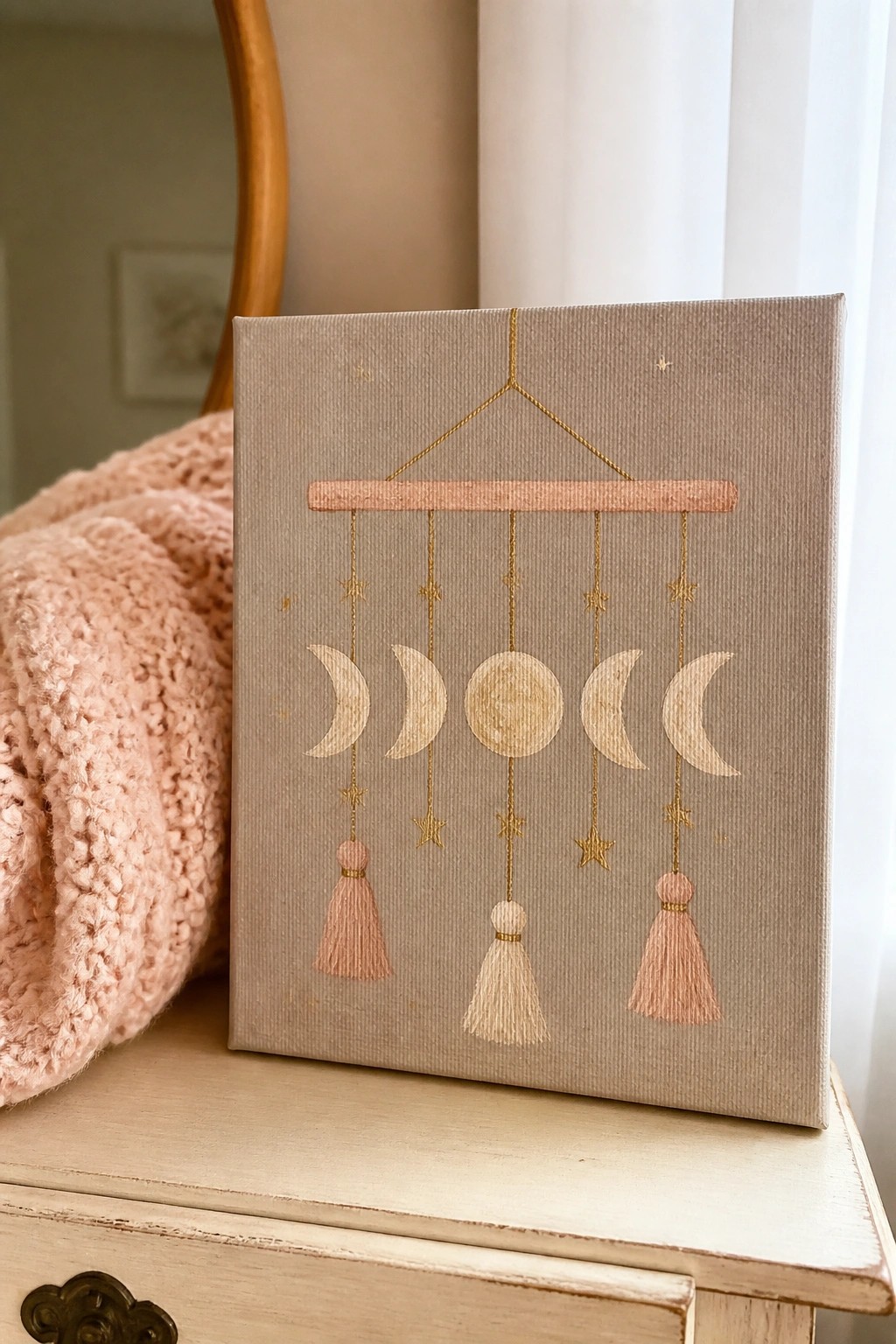 Canvas artwork of moon phase mobile with pink tassels and gold stars on beige background