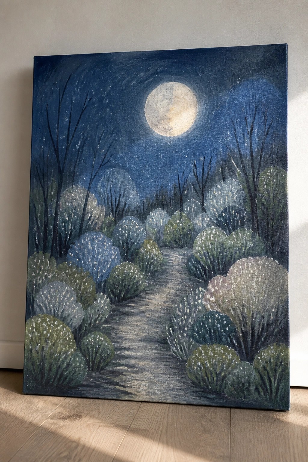 Full moon over winding path through speckled bushes and bare trees in night sky.
