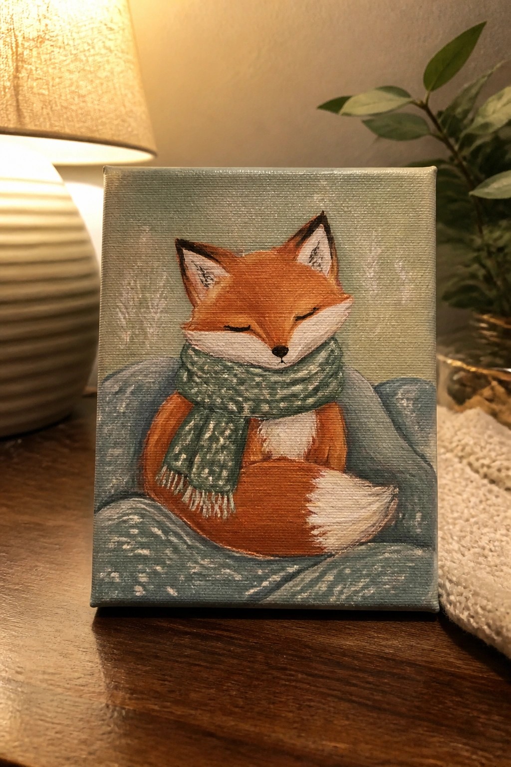 Cozy orange fox with green scarf curled on blue blanket in acrylic painting.