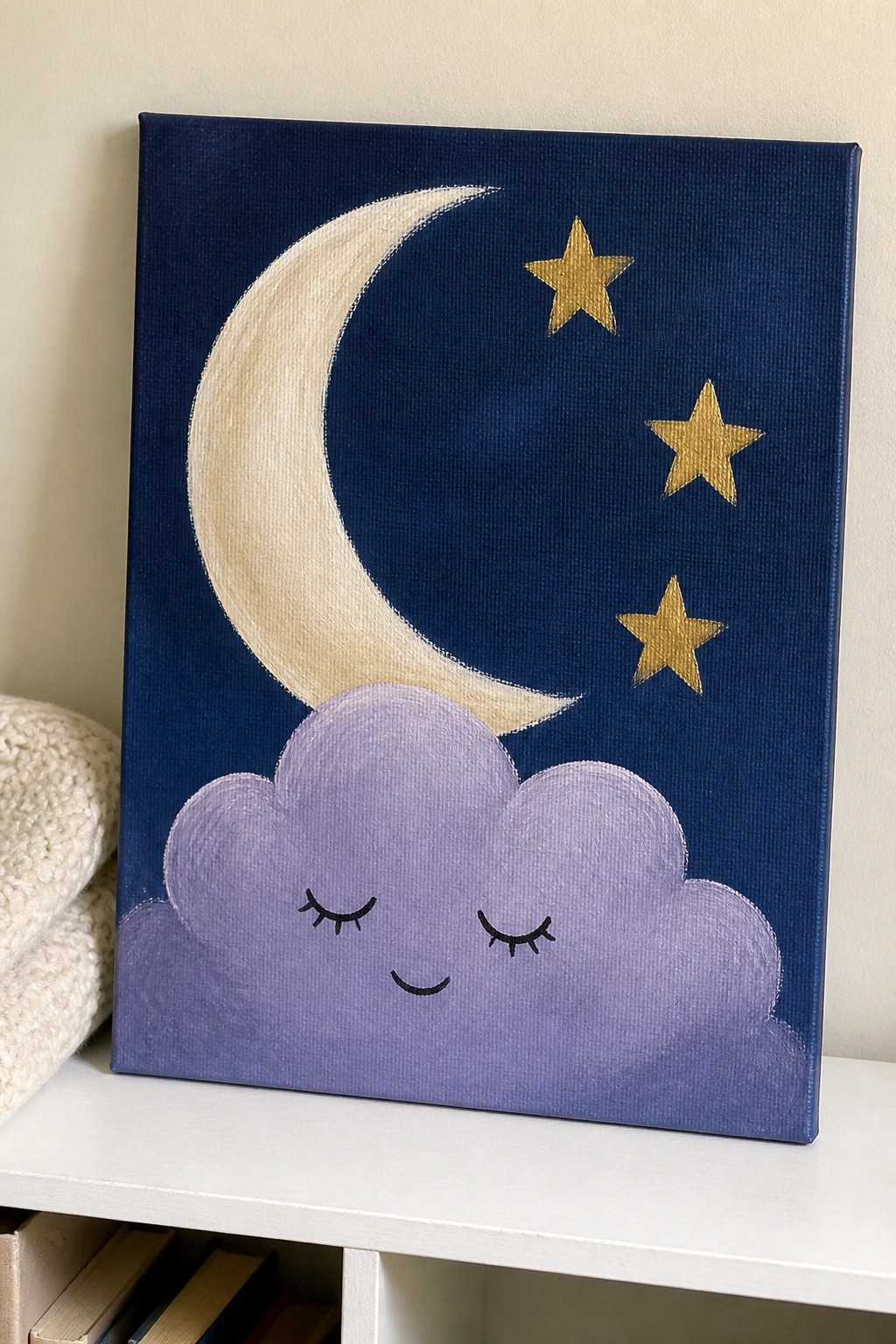 Navy canvas painting of smiling purple cloud, cream crescent moon, and three gold stars.