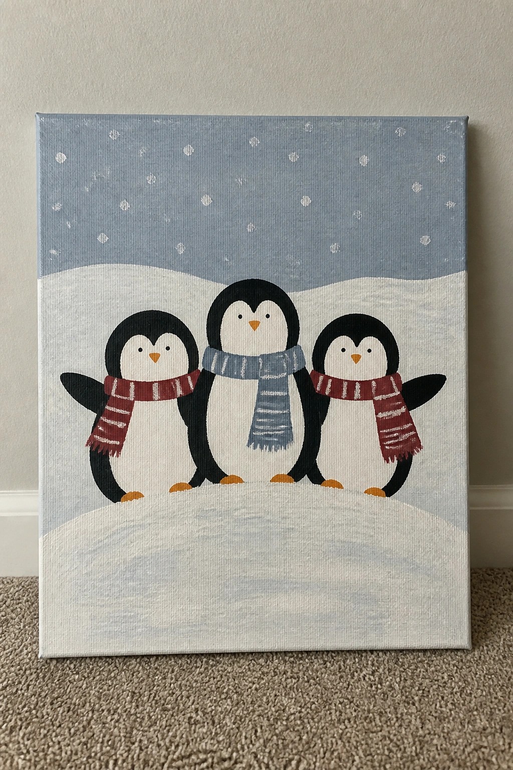 Three penguins wearing red and blue scarves on a snowy hill under a dotted sky.