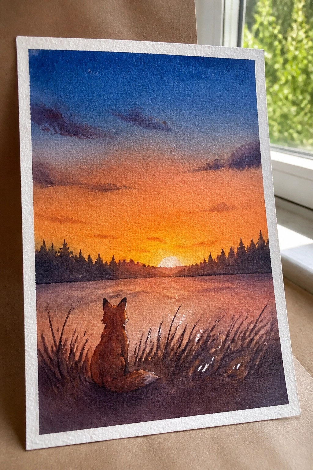 Watercolor painting of a fox watching an orange sunset over silhouetted pine trees.
