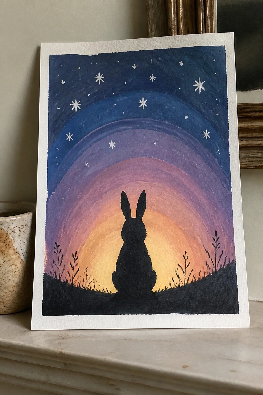 Watercolor painting of rabbit silhouette on hill under gradient starry sky