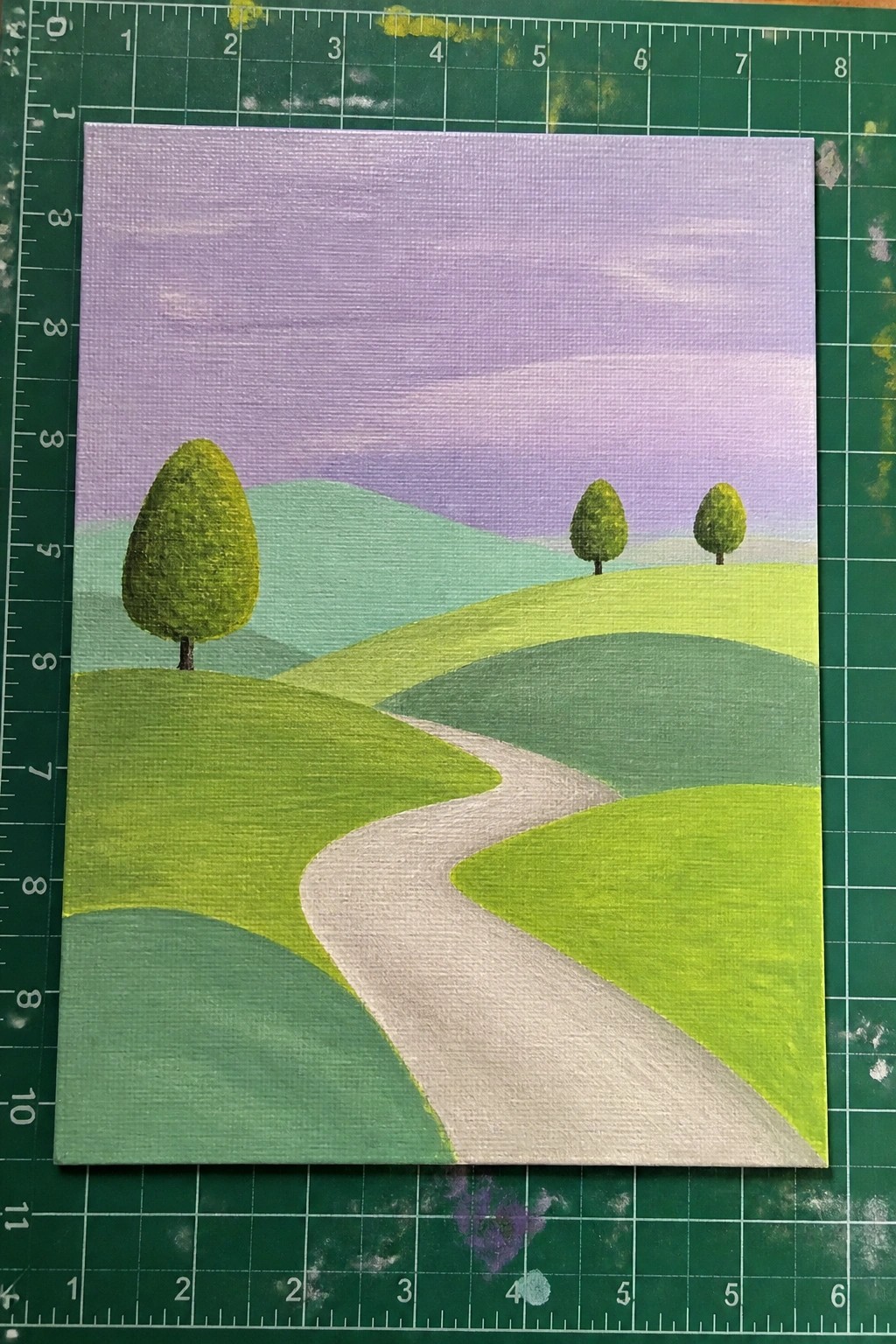 Winding path through layered green hills with trees under purple sky