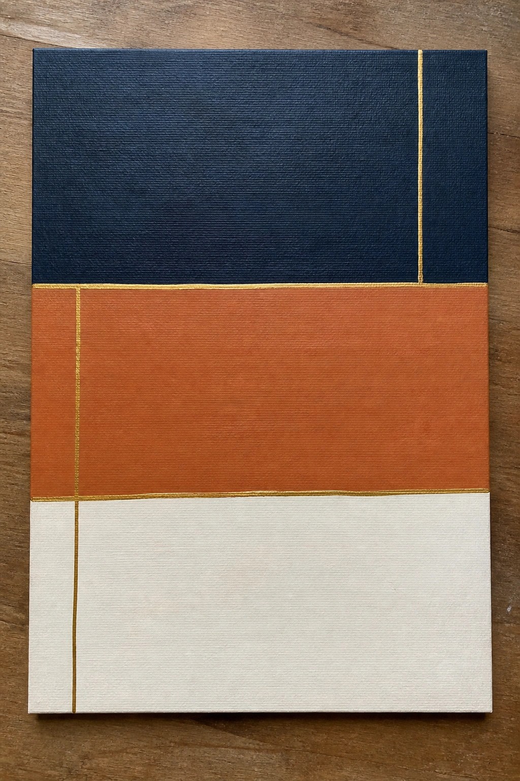Abstract geometric painting with navy blue, orange, and white sections divided by gold lines.