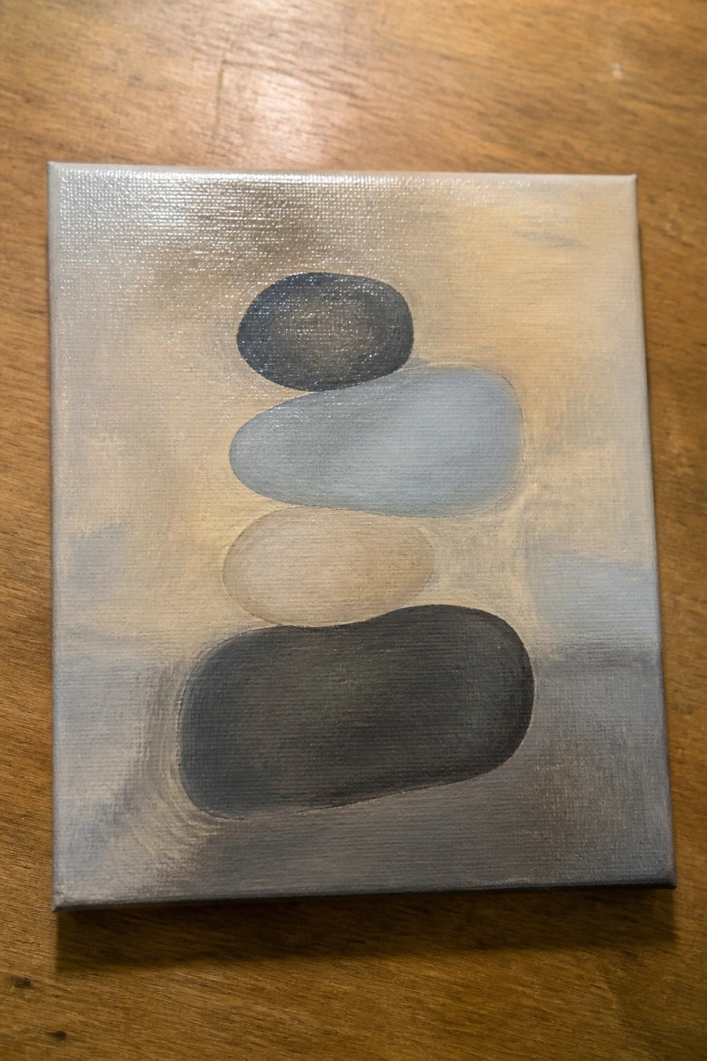 Abstract canvas painting of four stacked oval stones in gray and beige tones