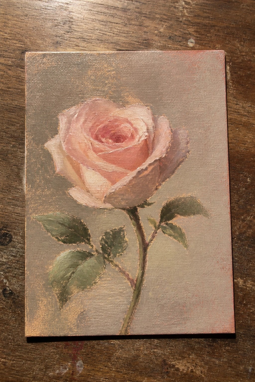 Pink rose with green leaves on stem, painted on canvas over wood.
