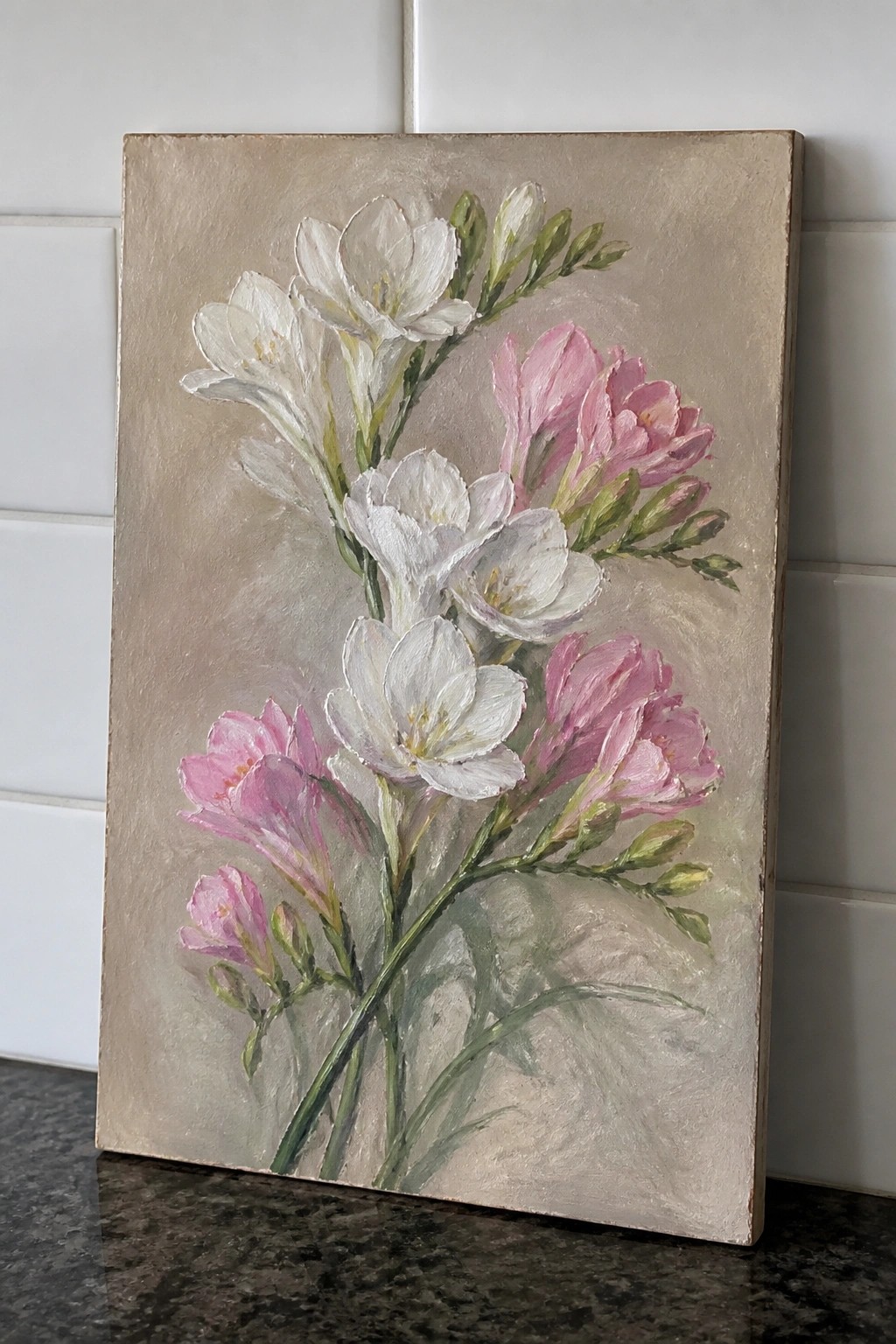 Painting of white and pink flowers on canvas against white tiled wall
