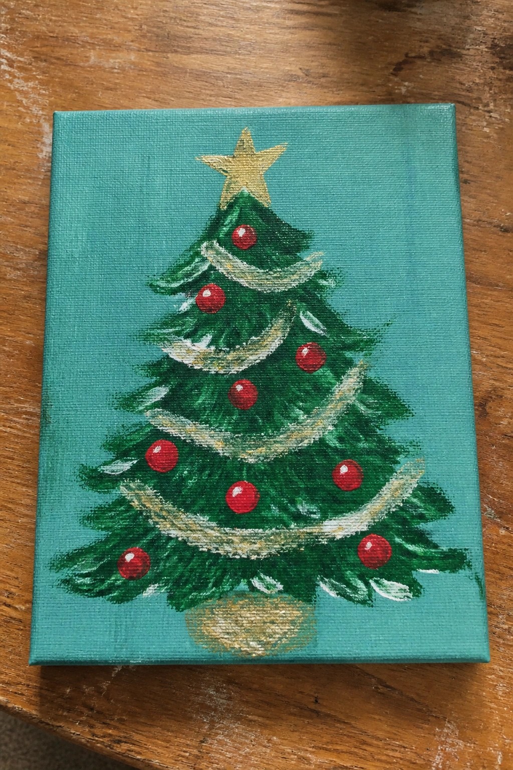 Green Christmas tree painting with red baubles, gold star and garland on teal canvas