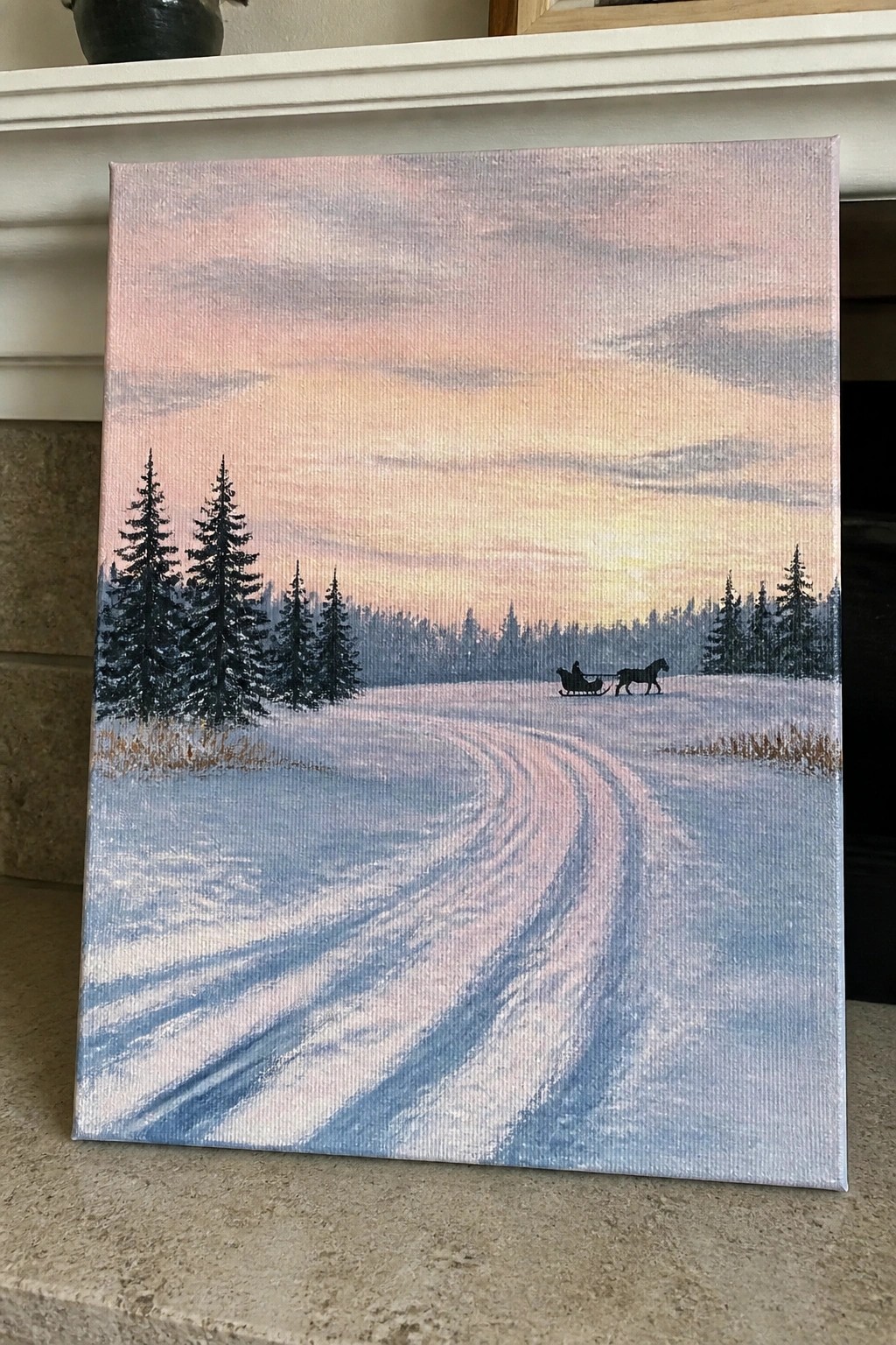 Winter painting of horse-drawn sleigh on snowy path through pine trees at sunset
