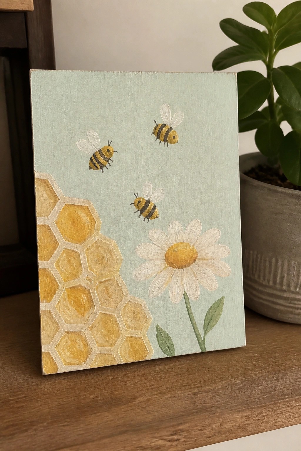 Yellow honeycomb, three bees, and daisy on light blue painted canvas