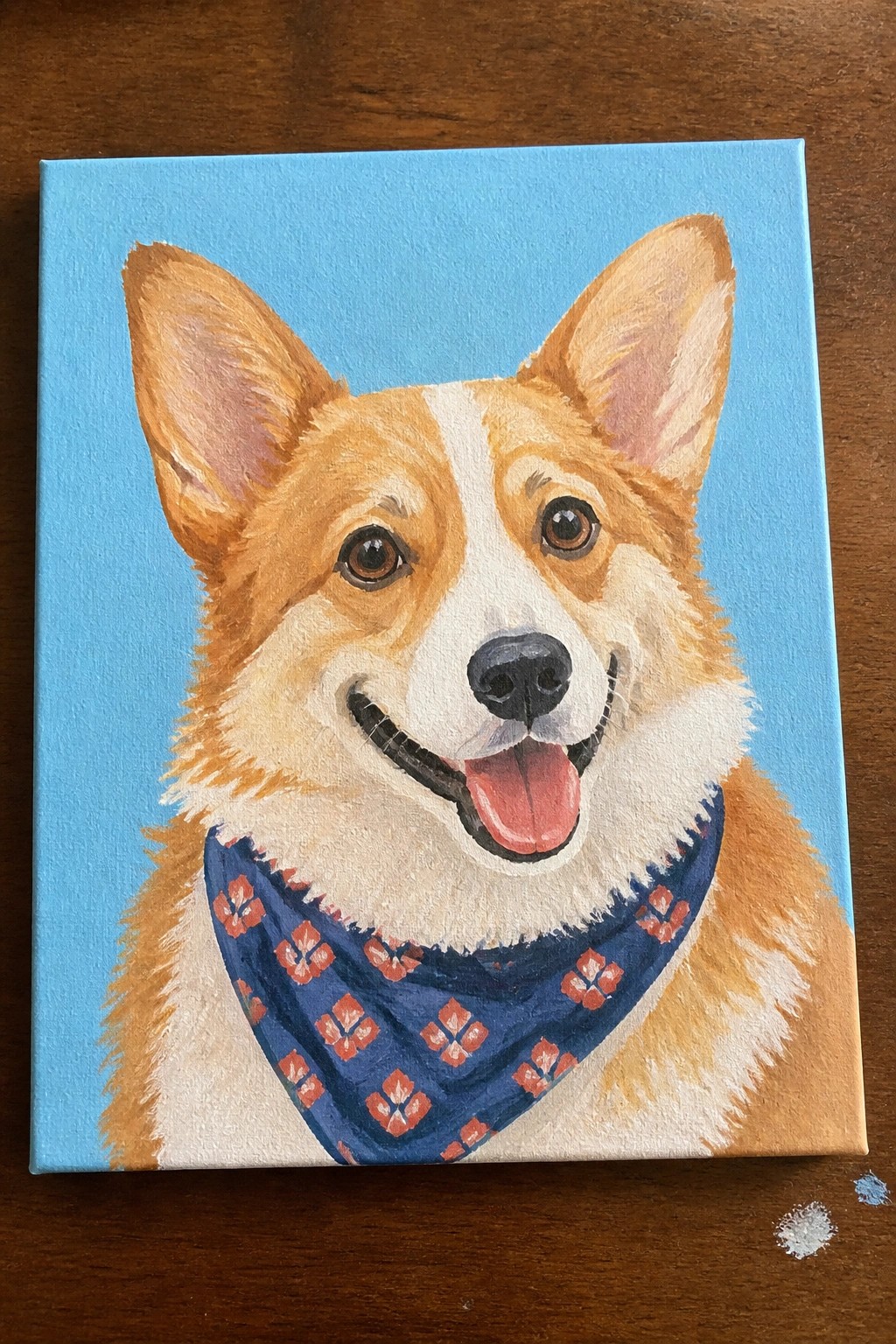 Acrylic painting of smiling corgi with orange fur wearing blue patterned bandana