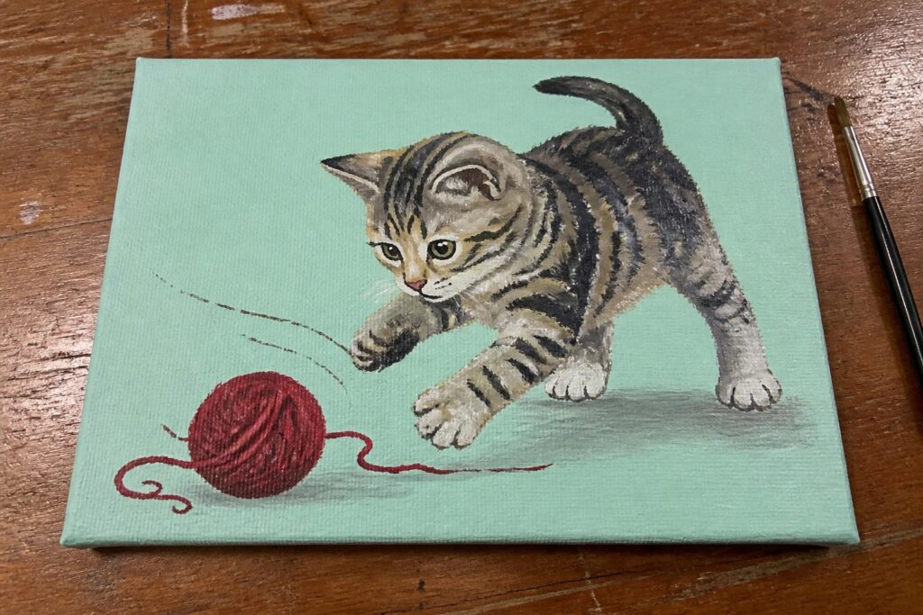 Realistic painting of tabby kitten reaching for red yarn ball on turquoise canvas.