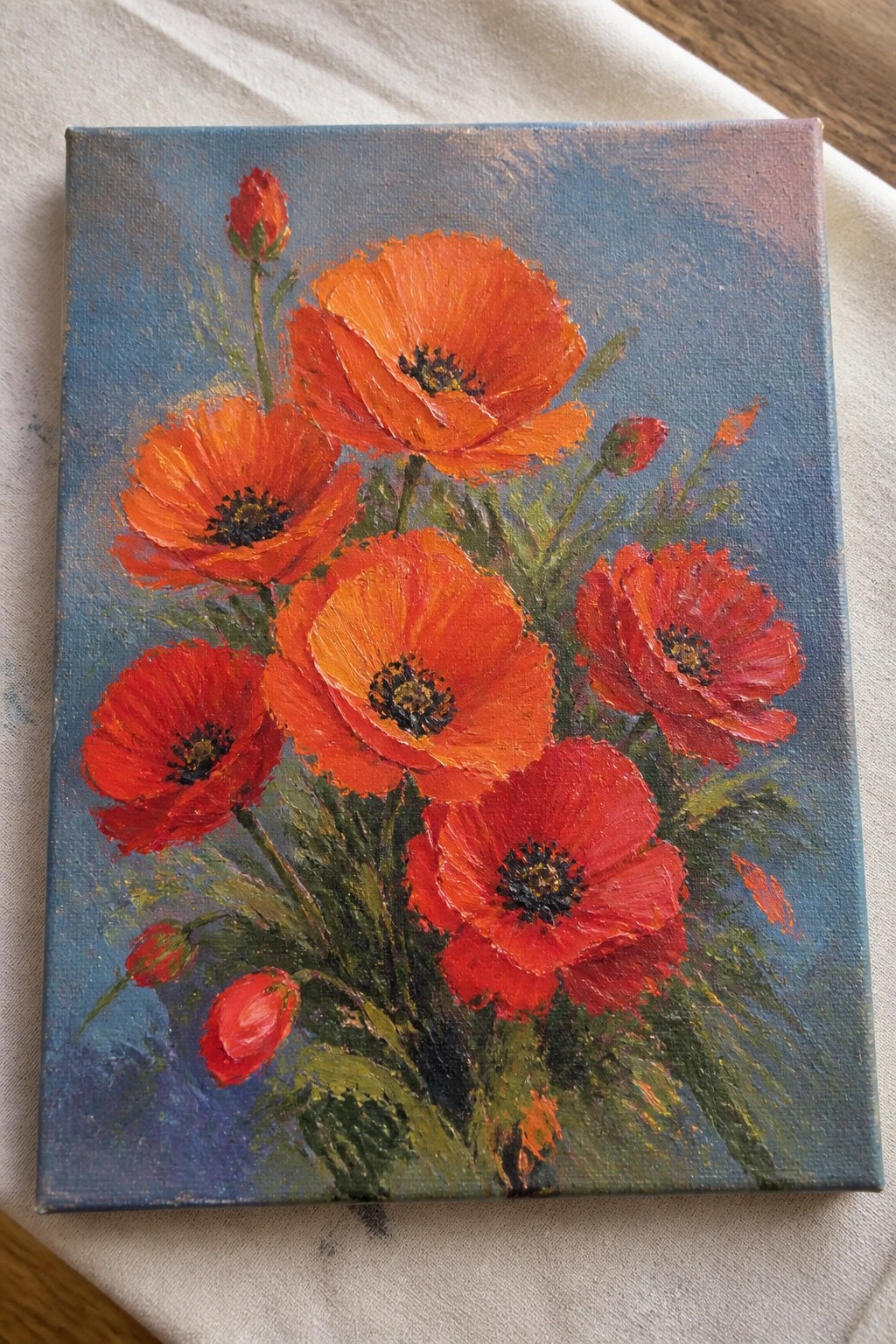 Vibrant oil painting of blooming red poppies with buds on blue canvas background