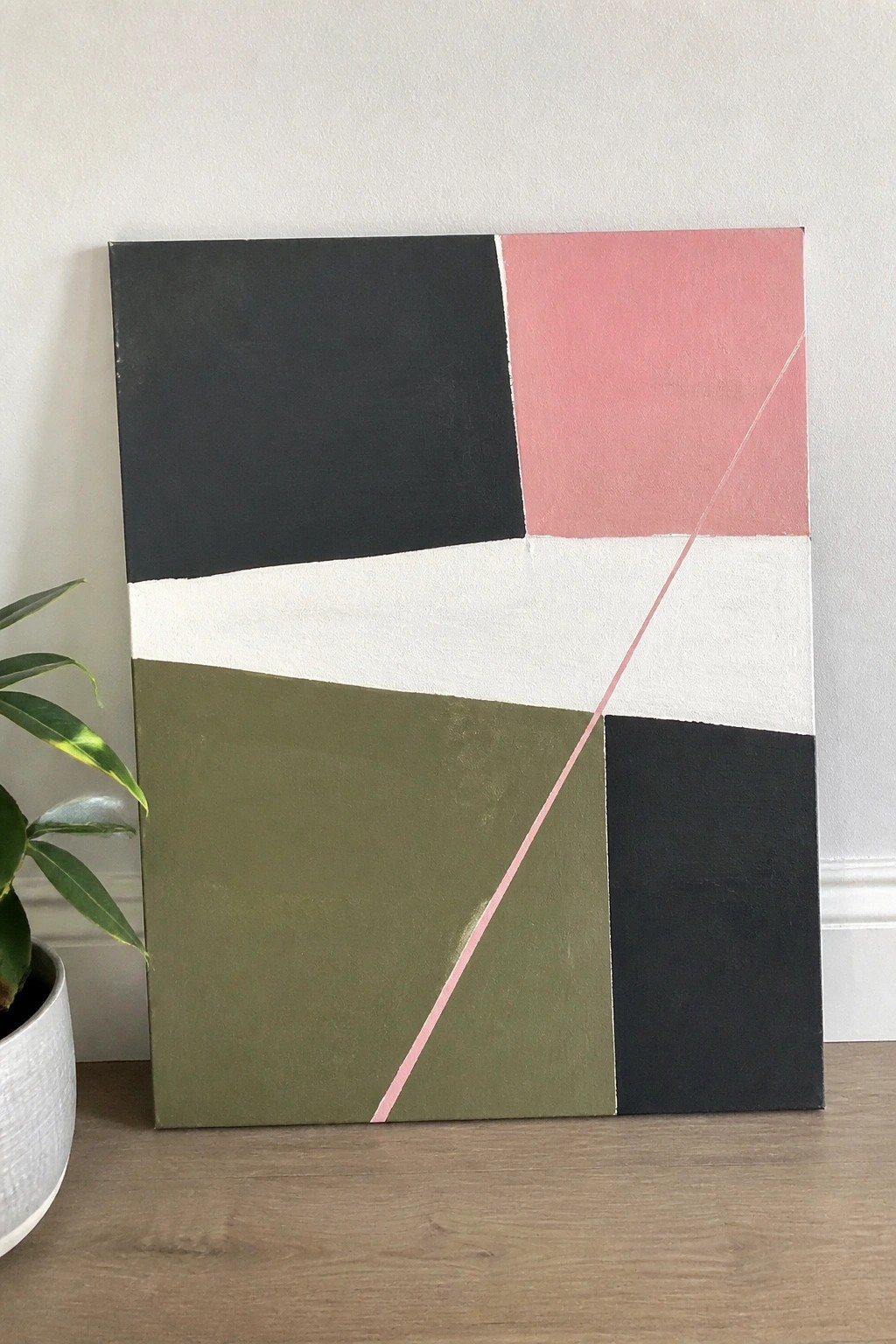 Abstract geometric painting with black, pink, white, olive green blocks and pink diagonal line