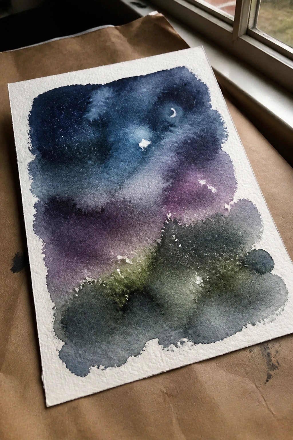 Watercolor night sky painting with blended blue, purple, green washes, stars, and crescent moon
