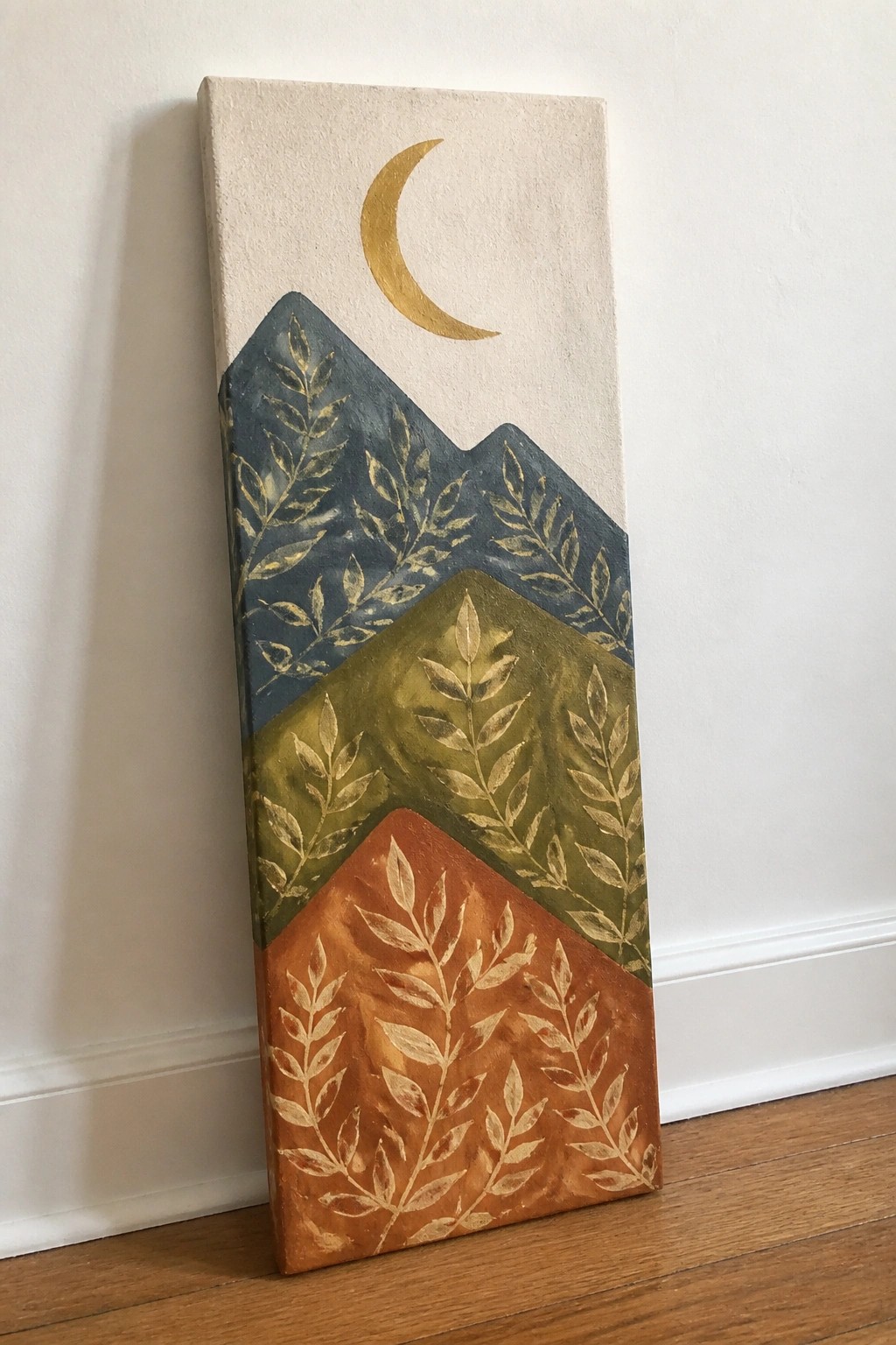 Vertical painting of gold crescent moon above layered blue, green, and orange mountains with gold leaves.