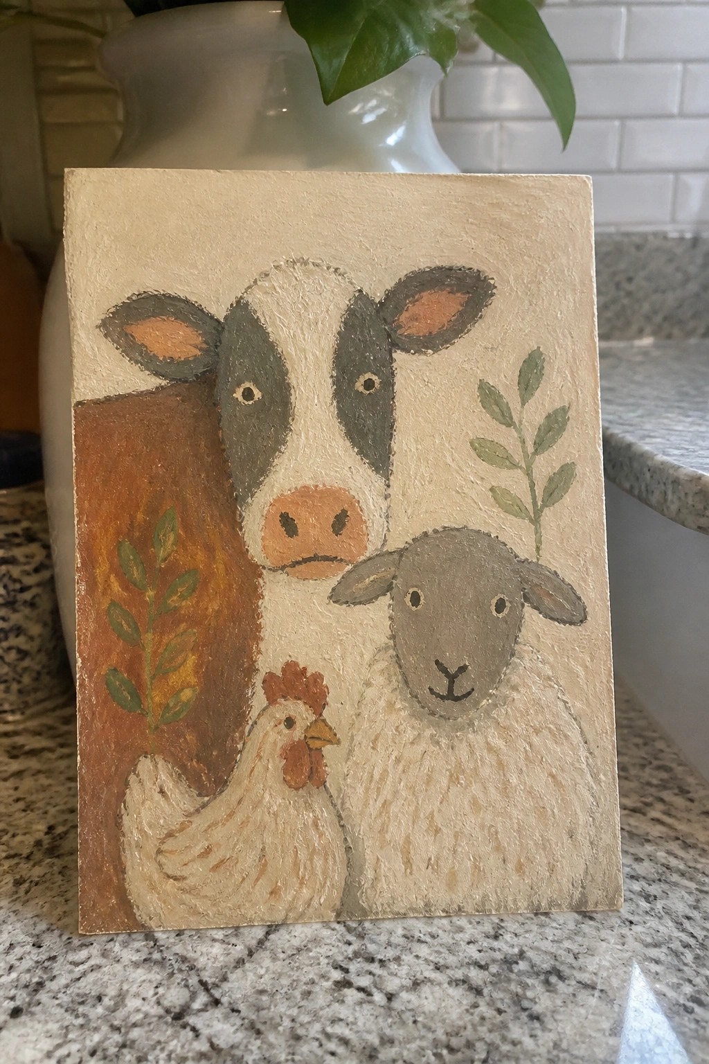 Folk-style painting of cow, sheep, chicken and green leaves on beige canvas.