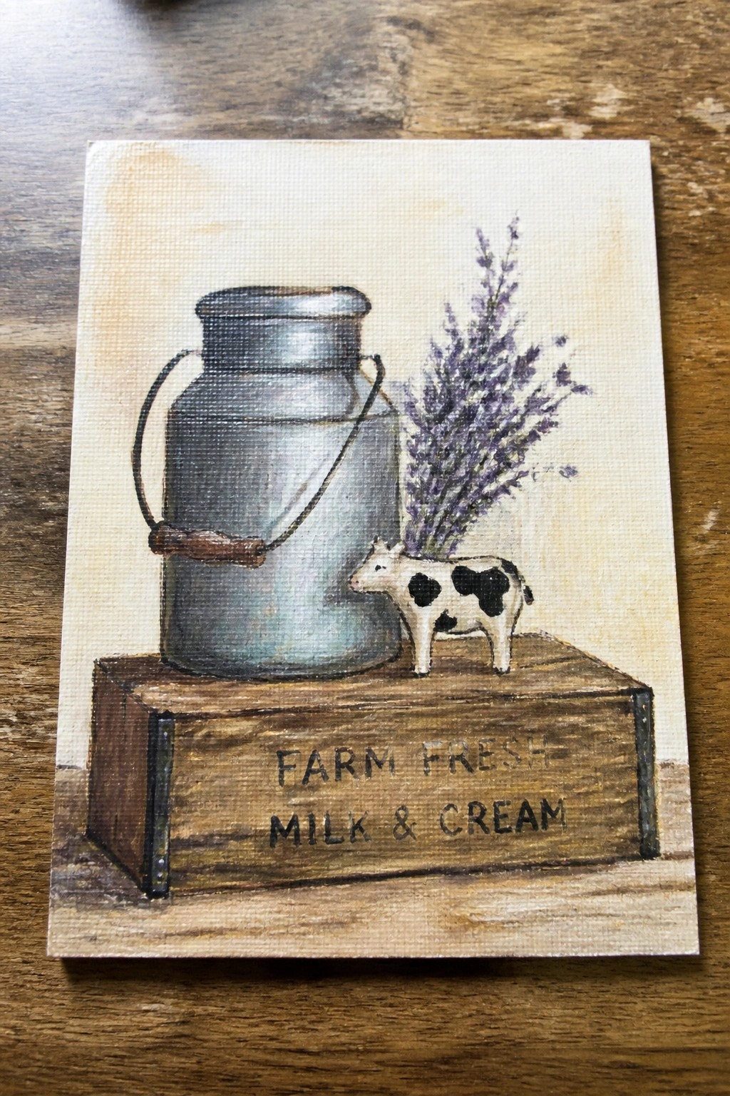 Rustic canvas painting of metal milk can, cow figurine, lavender on labeled wooden crate