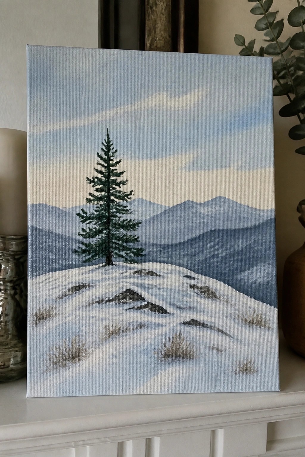 Painting of snowy hill with lone pine tree and distant blue mountains