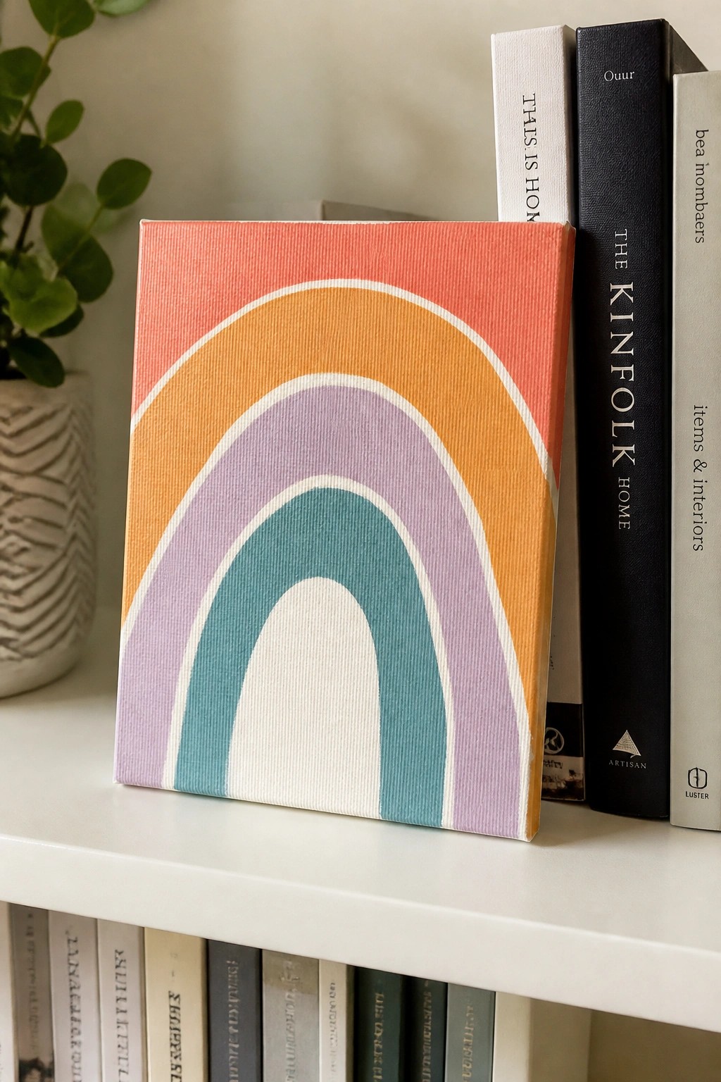 Rainbow canvas with coral, orange, purple, and teal arcs leaning on books.