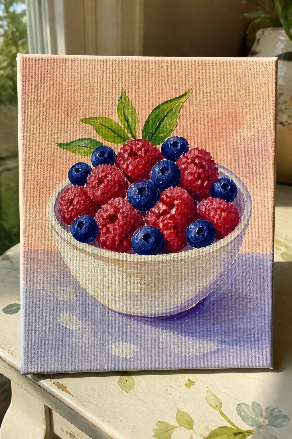 Still-life painting of raspberries and blueberries in white bowl on purple surface.