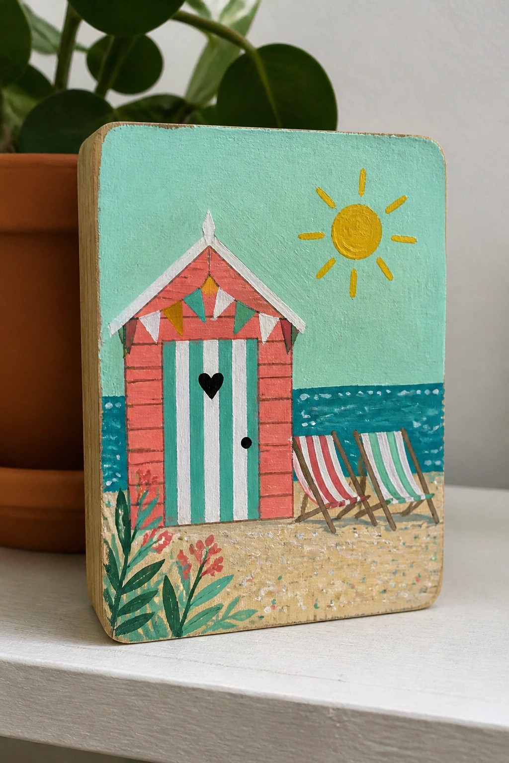 Colorful folk painting of beach hut, sun, sea and striped deck chairs on wood