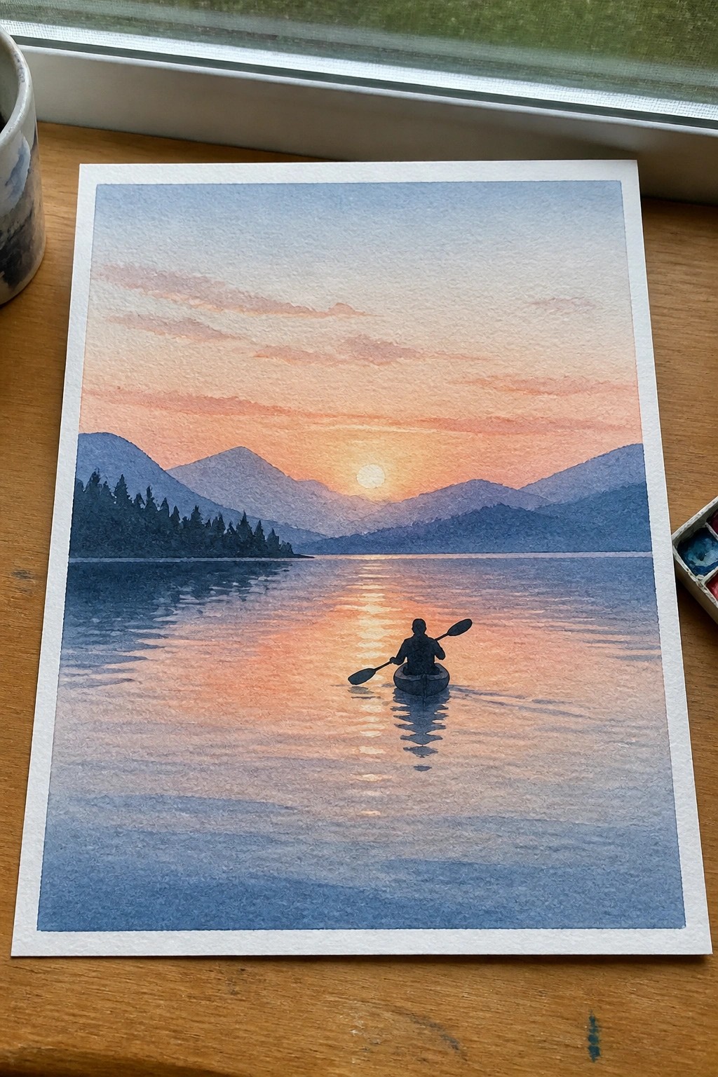 Watercolor of silhouetted kayaker on calm lake under orange sunset with mountains