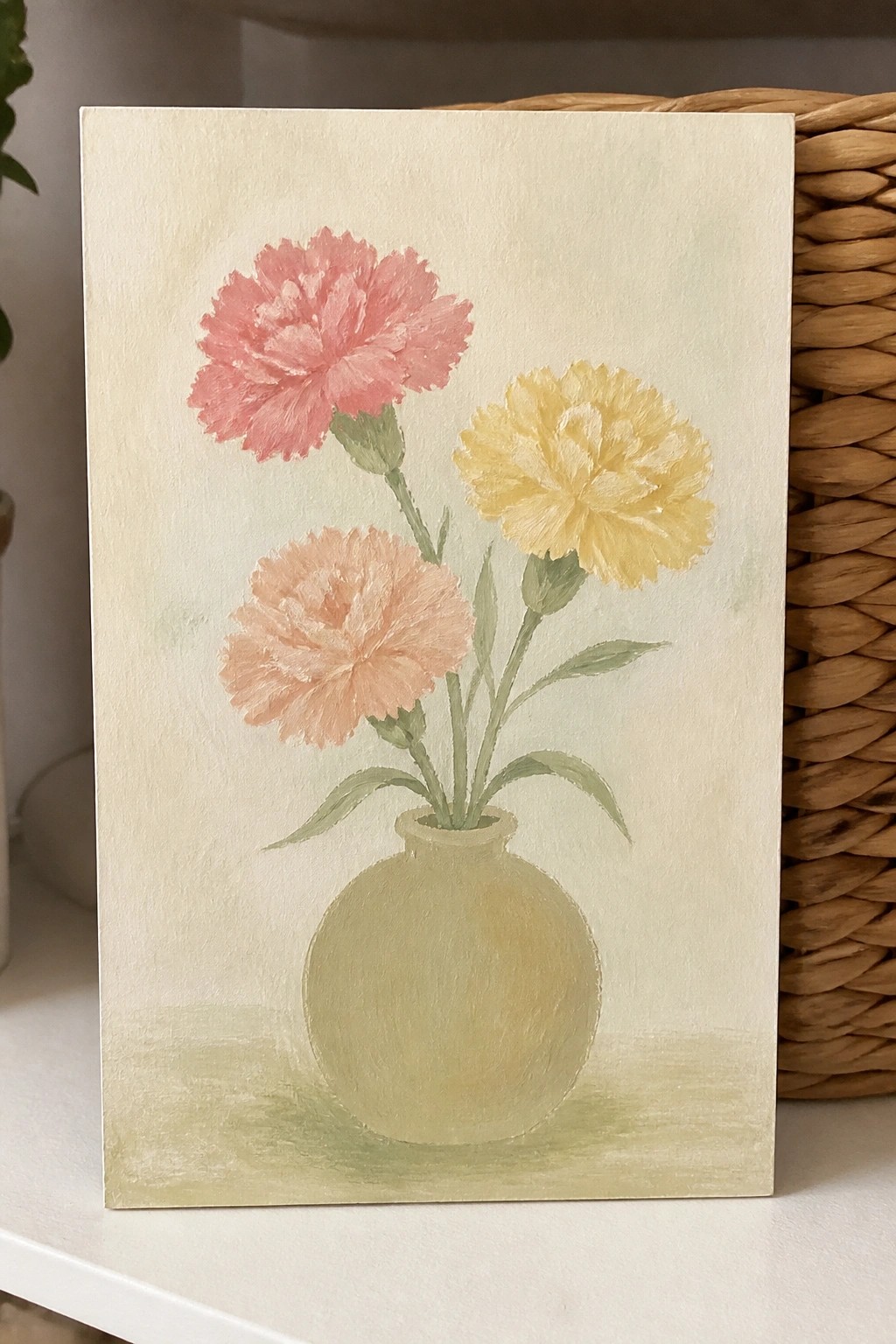 Three pink, peach, and yellow carnations in a round beige vase painting