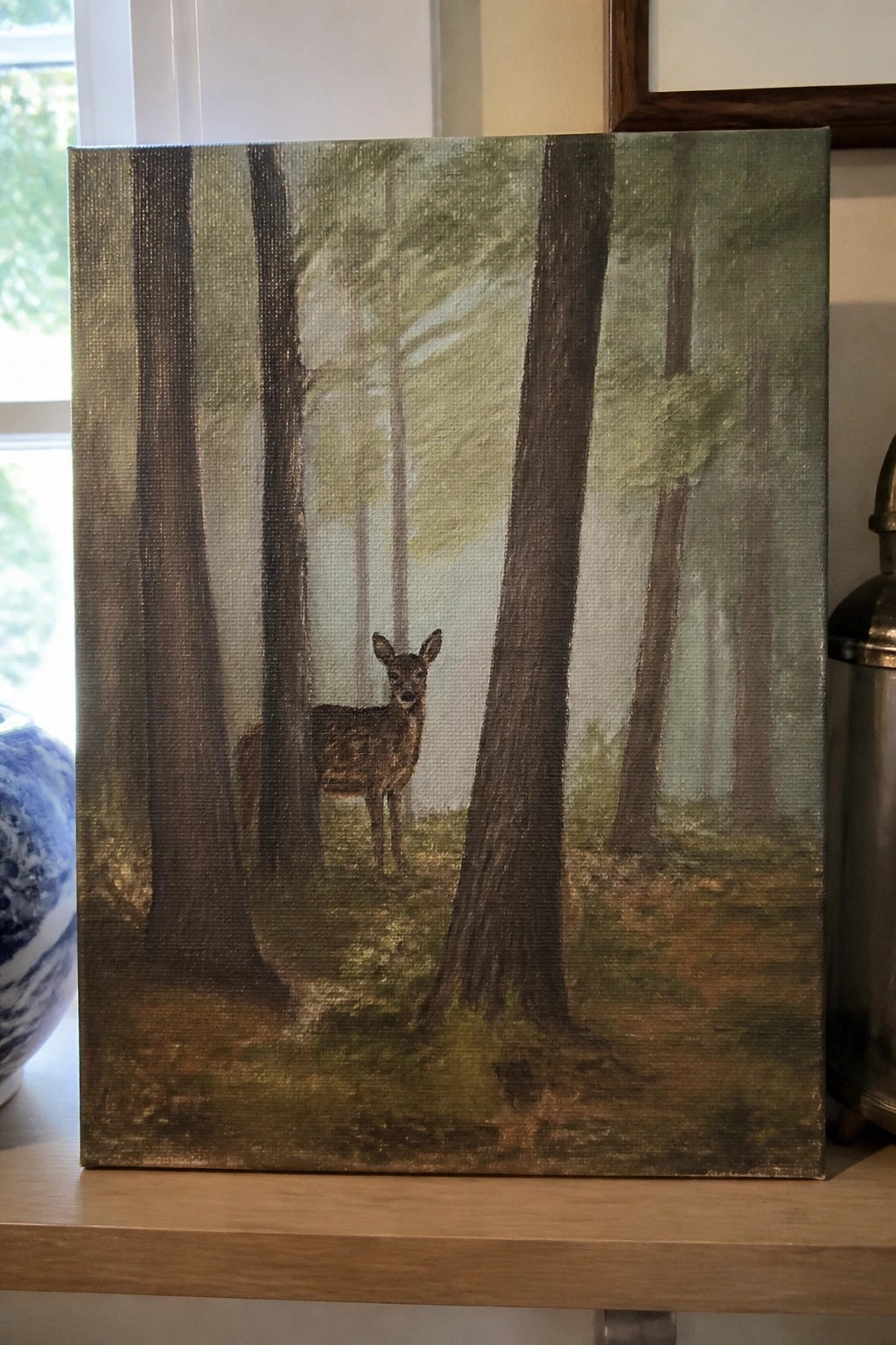 Canvas painting of a deer standing amid tall trees in a misty forest.