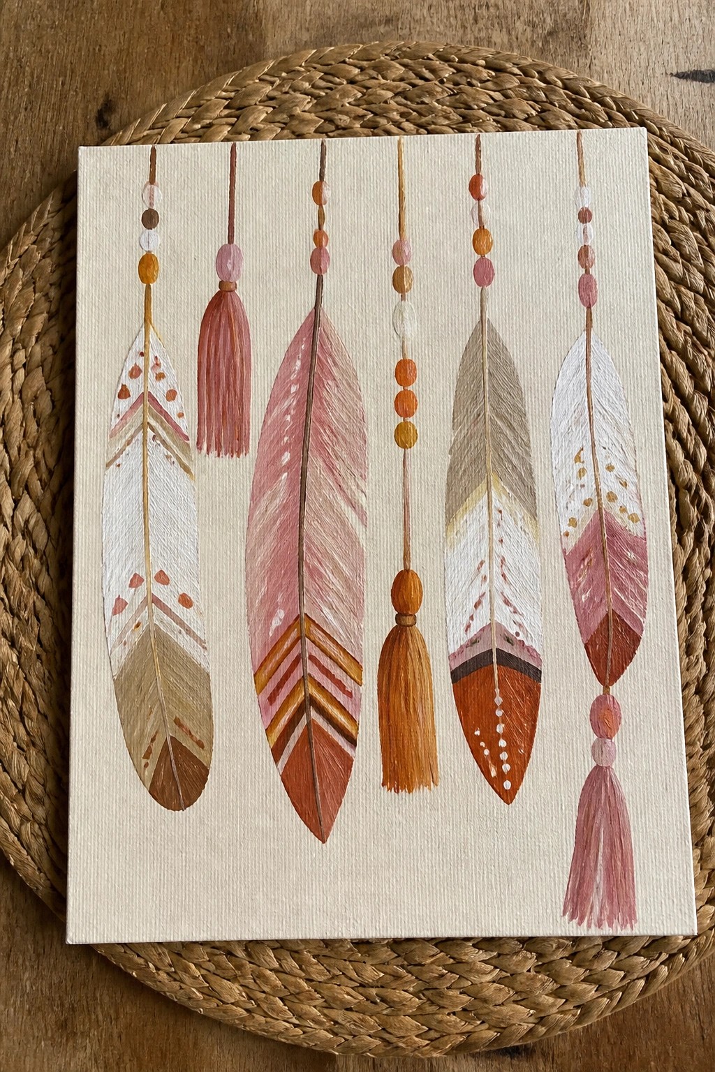 Canvas painting of five hanging feathers with beads and tassels in earthy tones