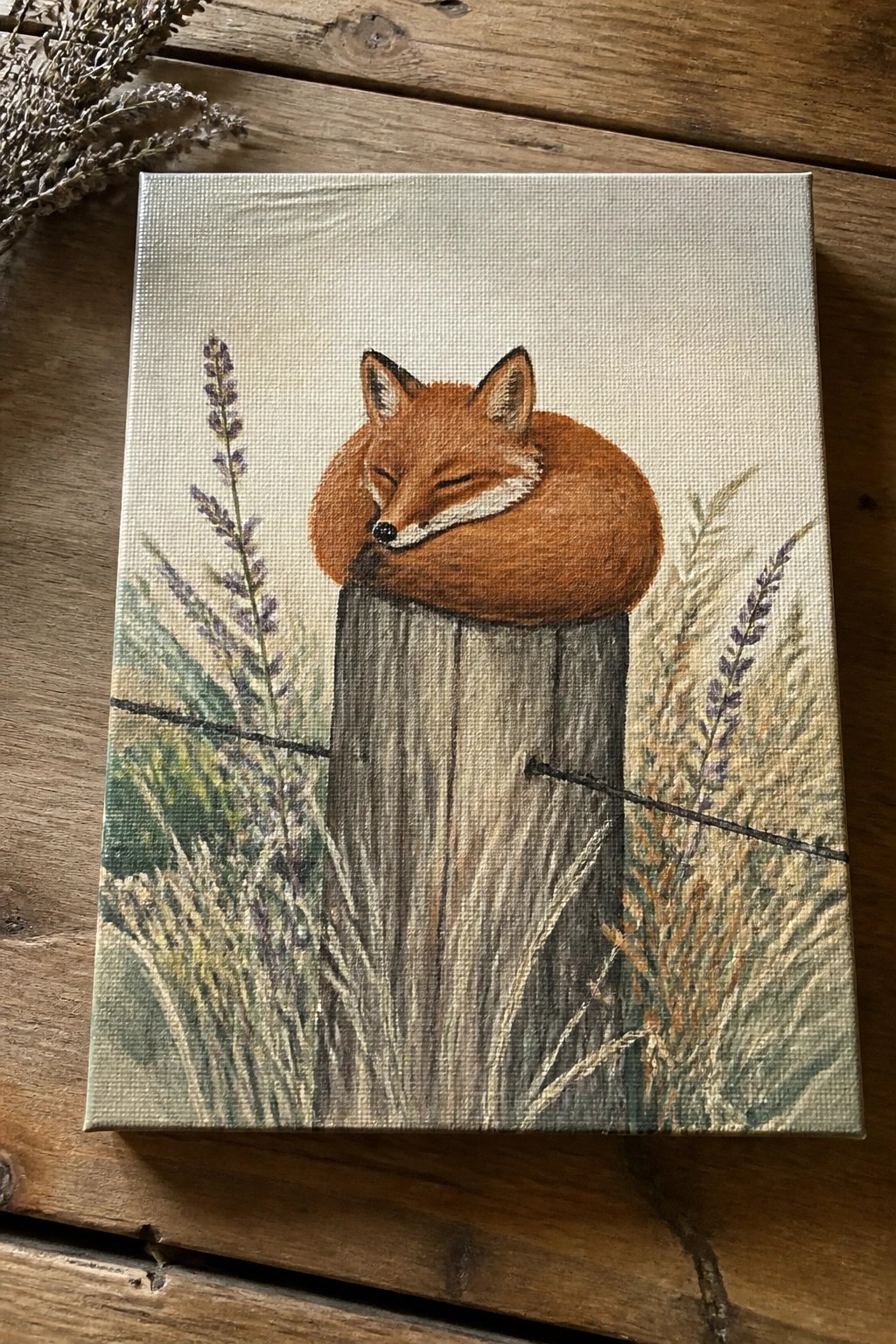 Sleeping fox curled on wooden post amid lavender, grasses, and wildflowers on canvas.