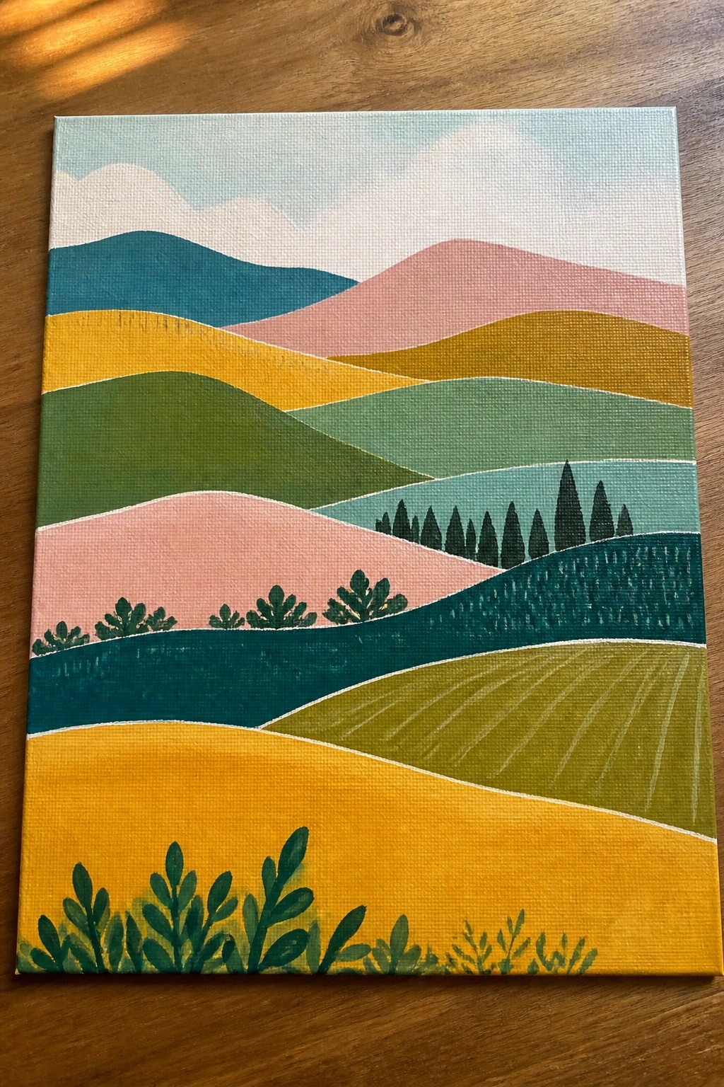 Colorful abstract landscape painting on canvas with layered hills, trees, and plants.