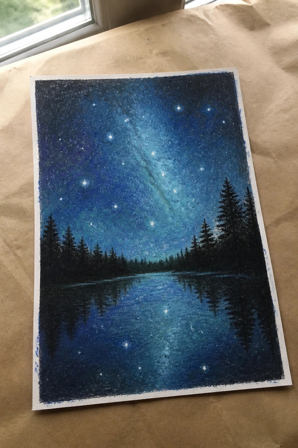 Chalk pastel painting of starry night sky over reflective lake with pine trees