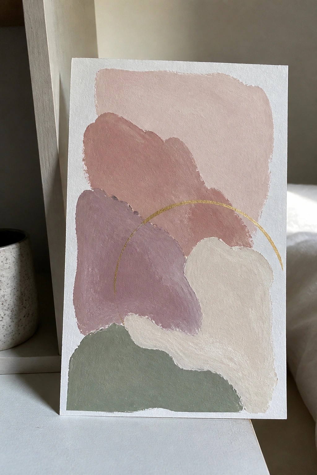 Abstract artwork with soft pink, mauve, beige, and green shapes plus gold arc.