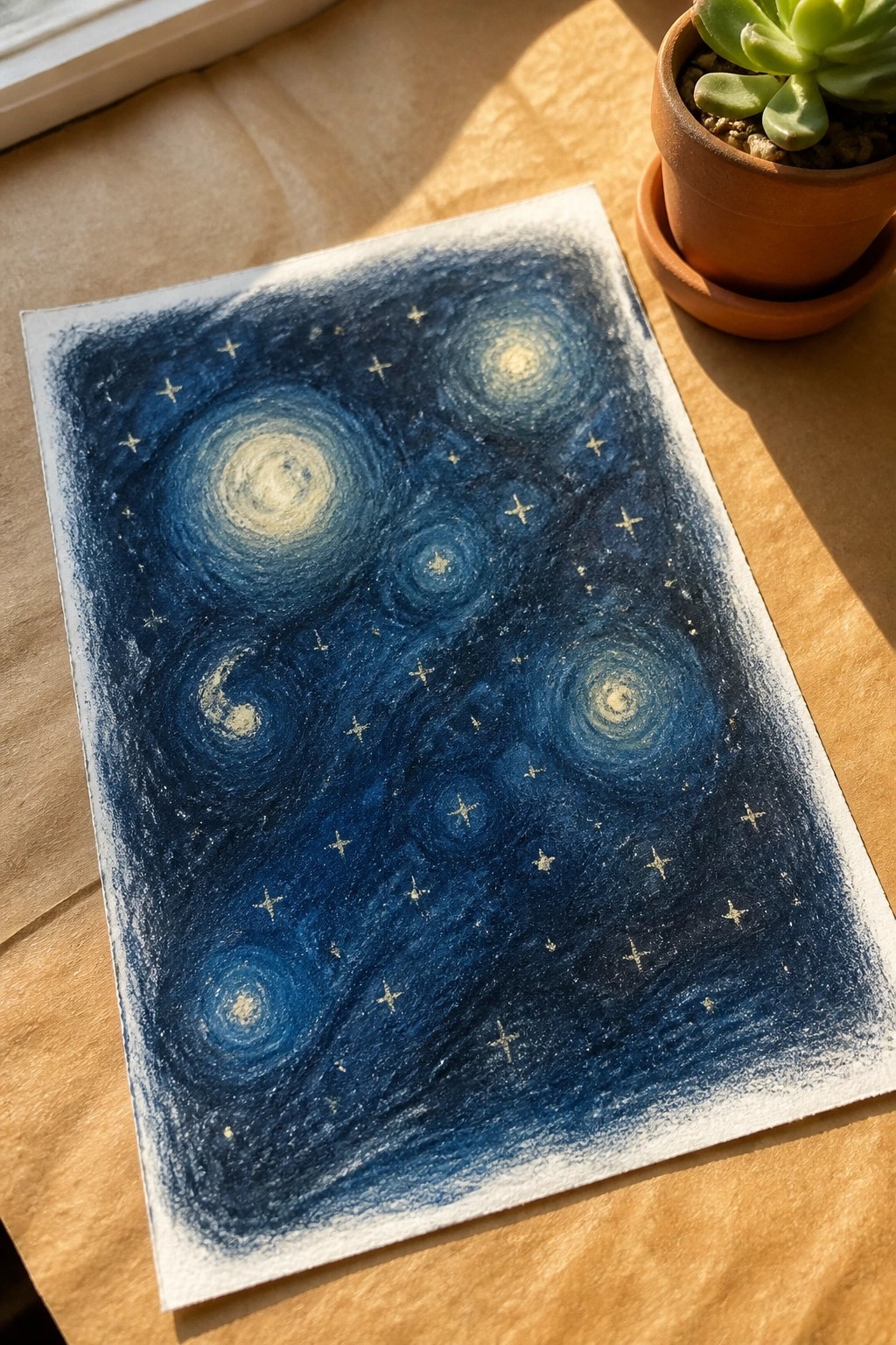 Blue swirling starry night painting with golden stars beside succulent plant