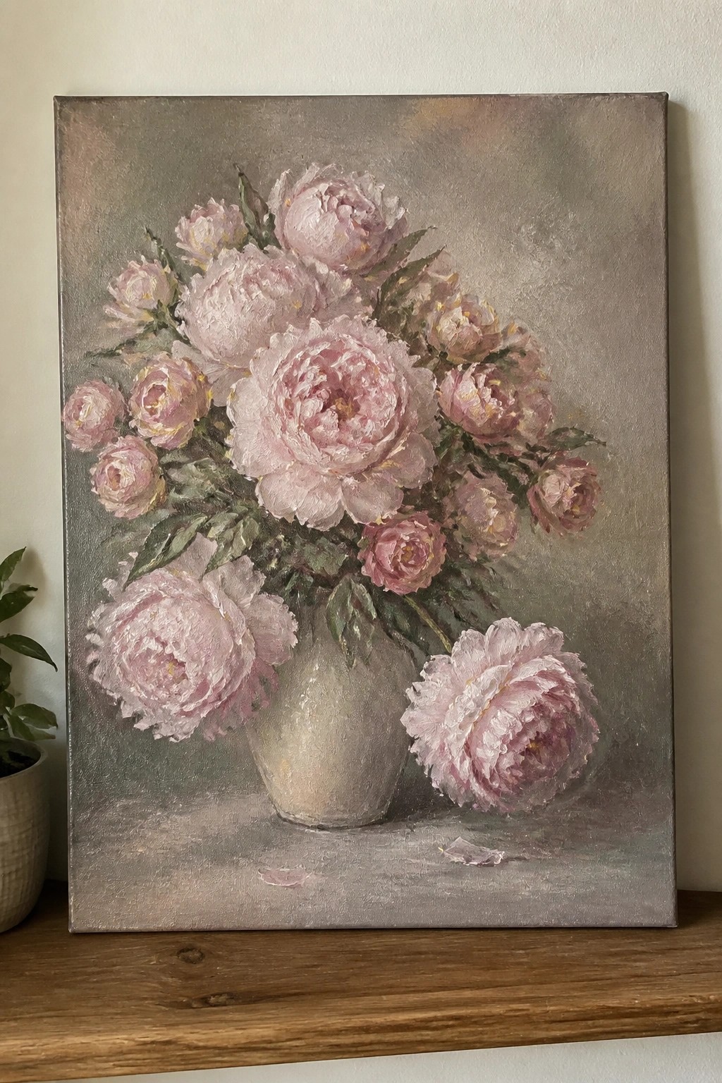A realistic oil painting of pink peonies in a gray vase with some flowers lying on the surface against a muted gray background.