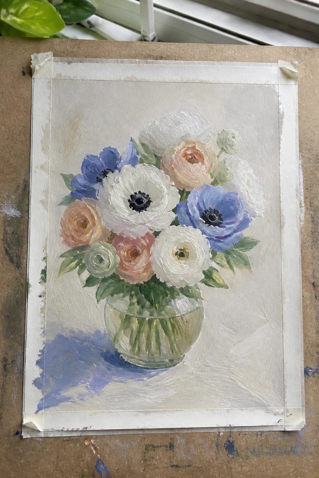 Still-life painting of white, blue, and peach flowers in a glass vase on a table
