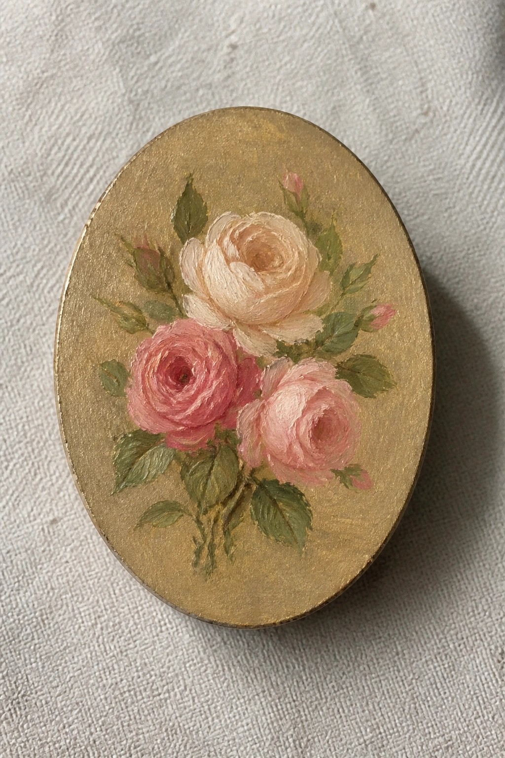 Oval gold painting of pink and cream roses with green leaves and buds