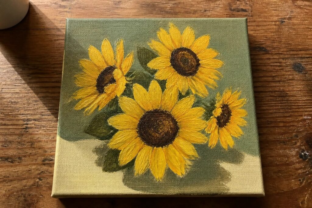 22 Gorgeous Flower Acrylic Painting Ideas That Instantly Brighten Any Room Four yellow sunflowers with brown centers on light green canvas atop wood.