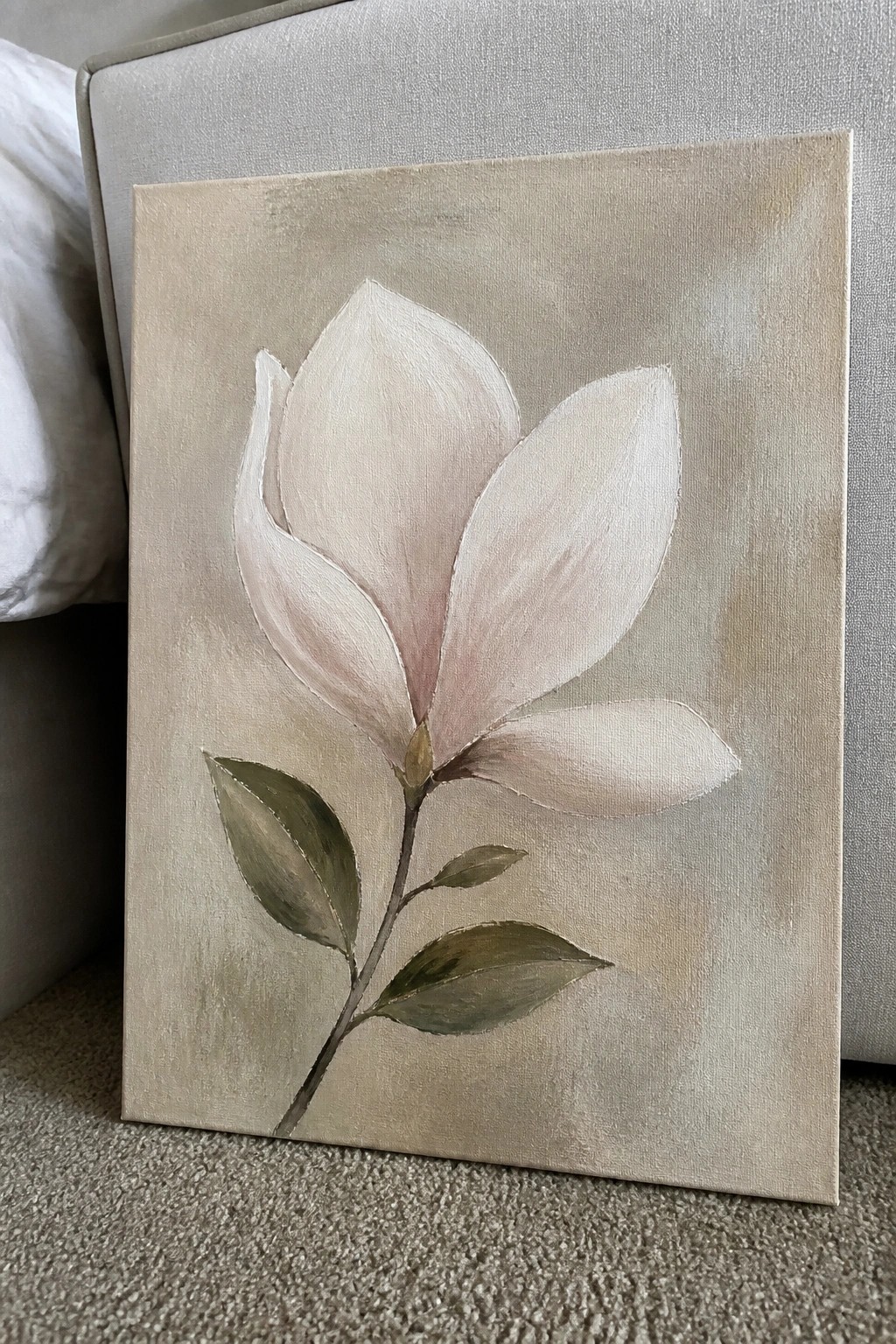 Canvas painting of soft pink magnolia flower with green leaves on beige background